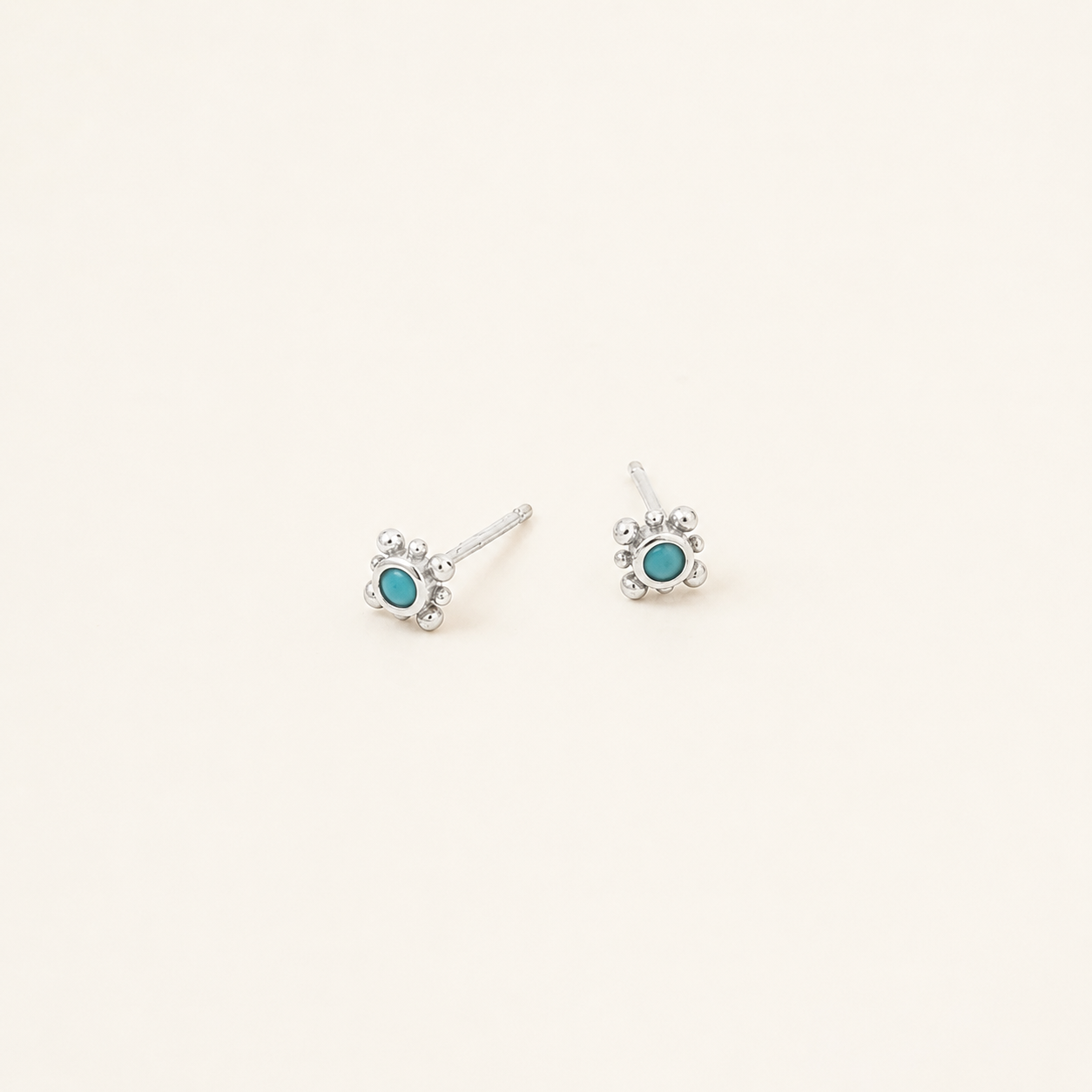 Pair of silver stud earrings with clear gemstones on a light gray background